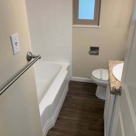 A white toilet sits next to a bathtub in a bathroom.